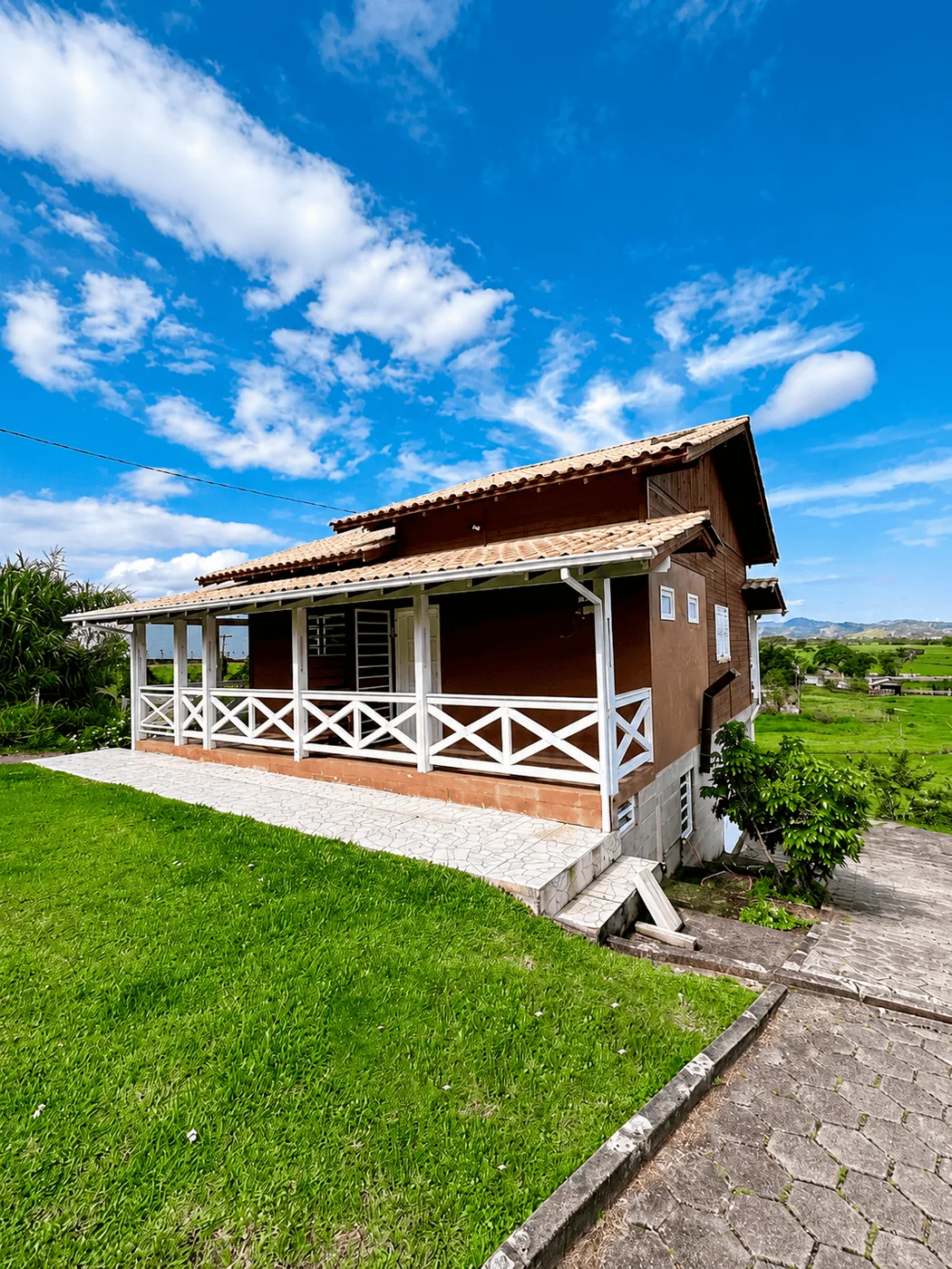 Casa de madeira de campo com varanda e cerca branca
