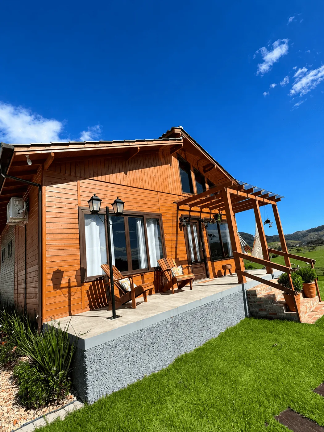Casa de madeira com pergolado e varanda ao sol